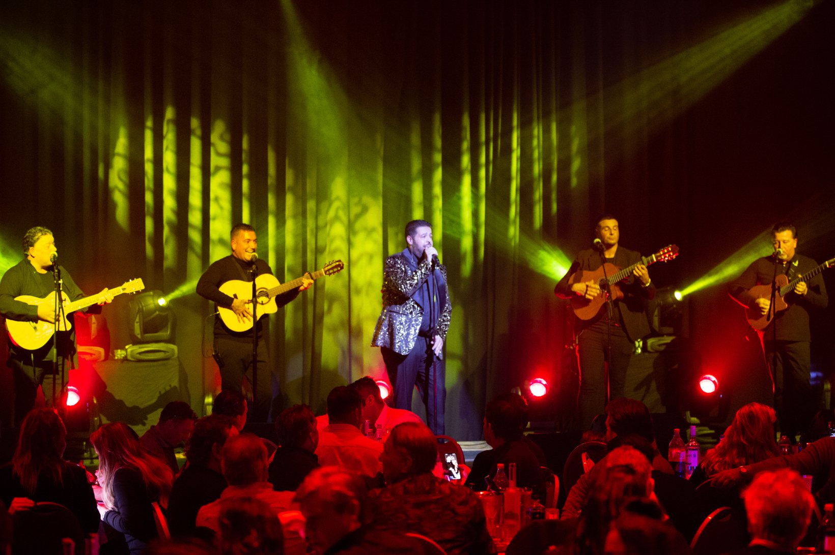 Janah Louard zingt met zijn band voor een volle zaal aan tafels